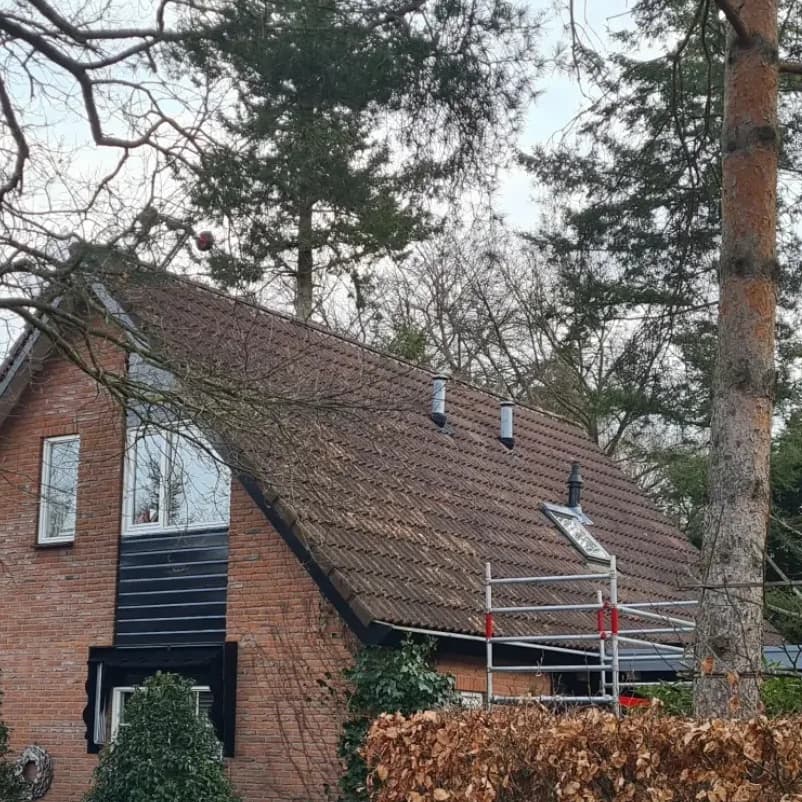 Woonhuis met verweerd bruin pannendak en een steiger tegen de zijgevel voor aanvang van de werkzaamheden.